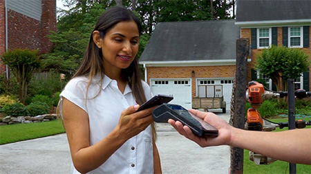 Woman paying her landscaper with mobile pay